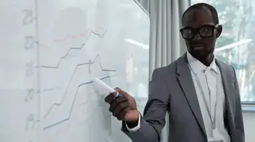 An advisor pointing at an investment chart on a whiteboard